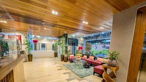 A hotel lobby with wooden flooring, red seating, and potted plants. - Uncle Tom's Cabin Hotel (Cebu City)