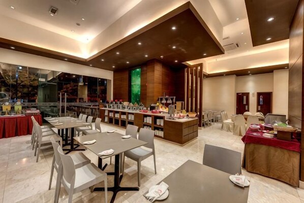 Un hall d’hôtel moderne doté d’un bar, d’espaces aménagés pour s’asseoir et offrant une vue sur l’extérieur.