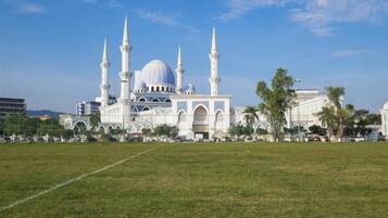 A large mosque with multiple minarets and a central dome, surrounded by a grassy field and a few trees.