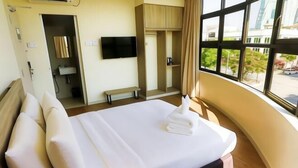 Une chambre d’hôtel avec un lit, une télévision, une armoire et une fenêtre donnant sur un paysage agréable.