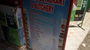 Ein Restaurantschild mit der Auflistung von Frühstücks- und Hauptspeisen inklusive Preise.