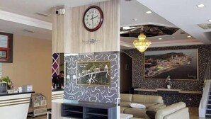 Un vestíbulo con una recepción, un reloj, un sofá y un cuadro grande en la pared.