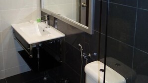 Un baño moderno con lavamanos, espejo y retrete blancos.