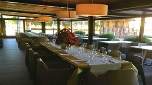 Un restaurant avec de longues tables, des chaises et des lampes suspendues.