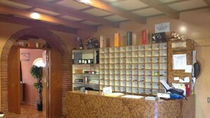 Un comptoir d’accueil avec un revêtement en marbre, une plante et un téléphone fixé au mur.