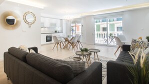 A modern living room with a sofa, a dining table with chairs, a kitchen in the background, and a balcony with outdoor furniture. - Large 4BR with AC Steps to the Beach (Alicante (Alacant))