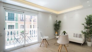 A modern living room with a white sofa, a dining table with chairs, and a balcony with outdoor furniture. - Large 4BR with AC Steps to the Beach (Alicante (Alacant))