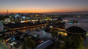 A coastal town at dusk with illuminated buildings, a marina with boats, and overwater bungalows. - Dragon Inn Floating Resort (Semporna)