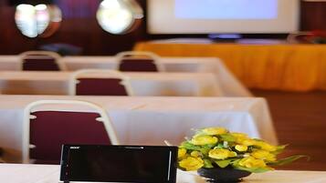 A conference room with tables, chairs, a laptop, and a bouquet of yellow flowers.