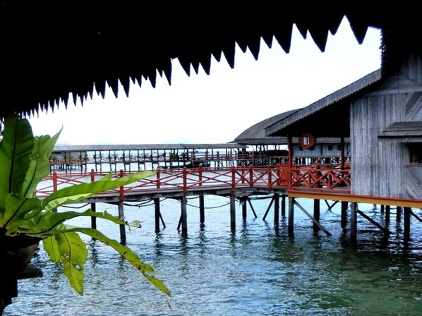 A wooden structure with a red bridge over water, likely a resort or lodge. - Dragon Inn Floating Resort (Semporna)