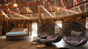 A rustic interior with wooden floors, hanging chairs, and a rustic ceiling. - Dragon Inn Floating Resort (Semporna)