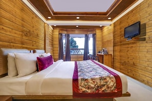 A wooden-paneled room with a bed, a TV mounted on the wall, and a window with curtains.