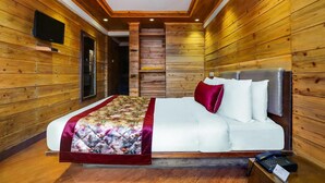 A wooden-paneled room with a bed, a television, and a staircase. - Summit Grace Hotel Spa (Darjeeling)