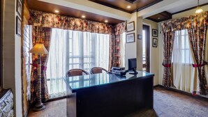 A room with a glass desk, two chairs, a lamp, and floral curtains. - Summit Grace Hotel Spa (Darjeeling)