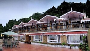 A hotel with multiple balconies, outdoor seating, and a well-maintained garden. - Summit Grace Hotel Spa (Darjeeling)
