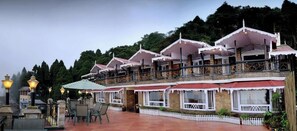 Un hotel con varios balcones, mobiliario exterior y un jardín bien cuidado.