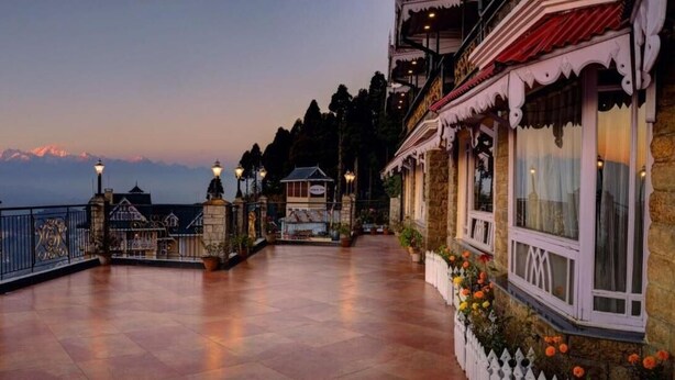 Un hotel con terraza, paredes de piedra y vistas a las montañas.