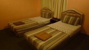 A hotel room with two single beds, each with a headboard and pillow. - Green View Motel (Kota Kinabalu)