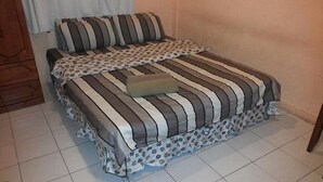A bed with striped bedding and a polka dot pillow. - Green View Motel (Kota Kinabalu)