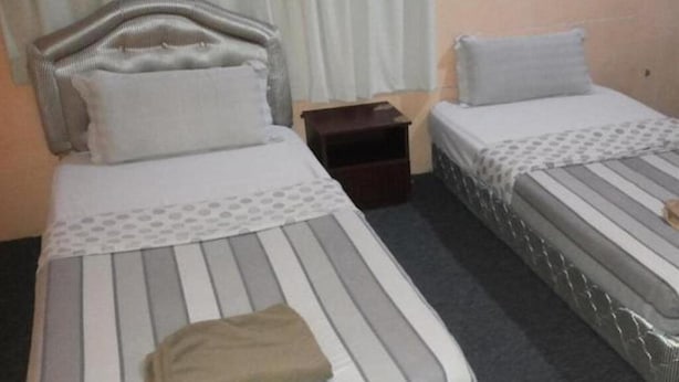 A hotel room with two beds, each with a headboard and pillow. - Green View Motel (Kota Kinabalu)
