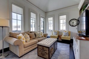 Ein Wohnzimmer mit einem beigen Sofa, einer Holzbank und einem Fernseher.