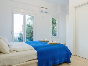 Une chambre à coucher avec un lit, une couvre-lit bleue et une fenêtre donnant sur un paysage verdoyant.