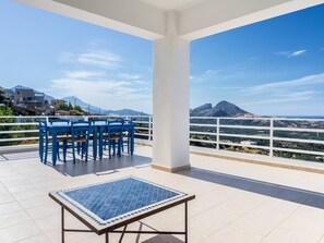Une terrasse avec une table et des chaises, un sol carrelé et une vue sur un paysage montagneux.