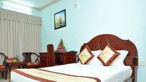 A hotel room with a bed, a desk, a chair, and a window with curtains. - Lam Son Hotel (Vung Tau)