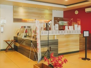 Un comptoir d’accueil au design moderne, une horloge au mur et un mur d’accent de couleur rouge.