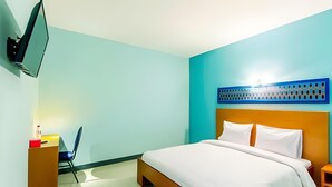 A hotel room with a bed, a desk, a chair, a TV mounted on the wall, and a decorative wall panel. - New Moonlight Hotel (Bandung)