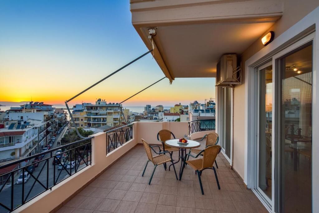 Ein Balkon mit Tisch und Stühlen mit Blick auf eine Stadtlandschaft bei Sonnenuntergang.
