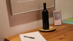 A wooden table with a framed artwork, a bottle, and a framed picture. - Guest house with a large terrace right by the pool (Murci)