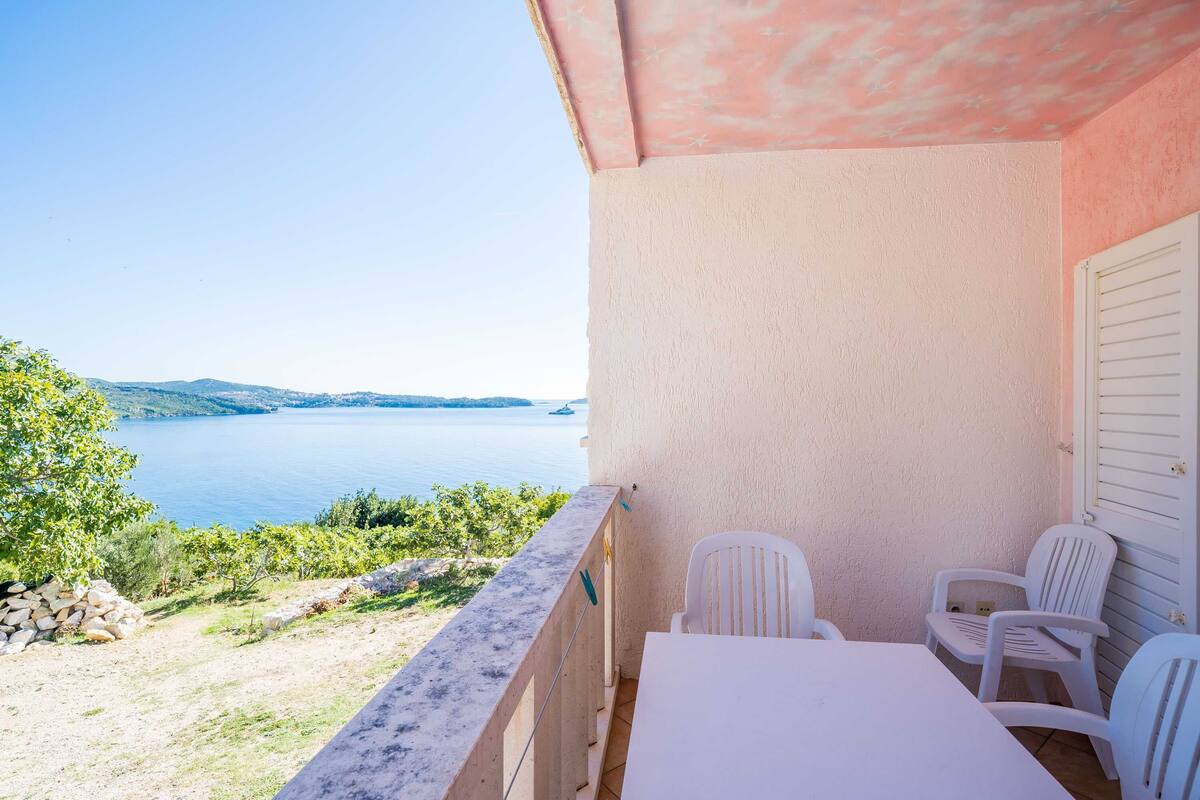 Ein Balkon mit Tisch und Stühlen mit Blick auf einen See und Hügel.