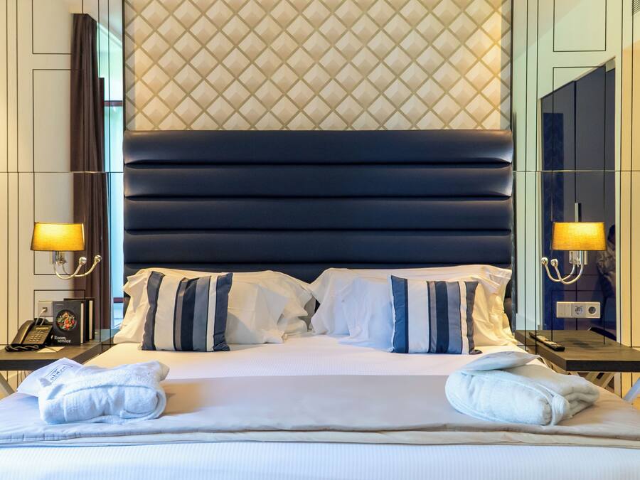 A hotel room with a large bed, two bedside tables, a nightstand, a telephone, and a lamp.