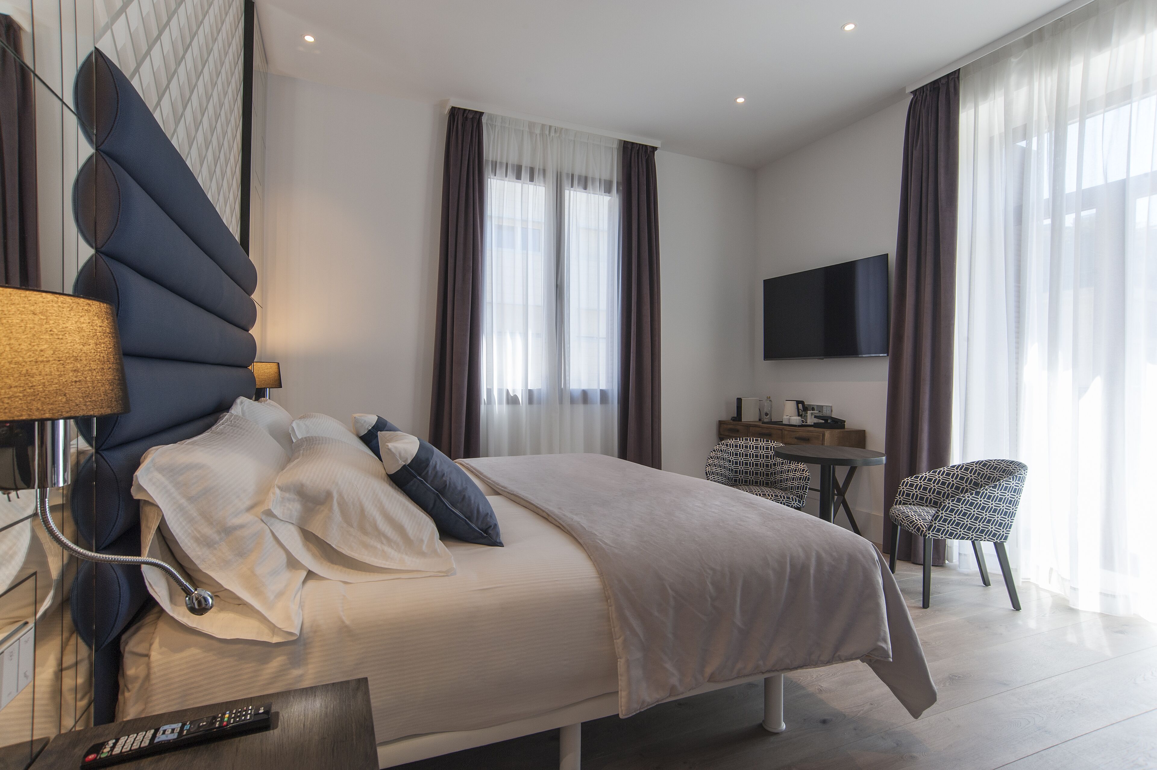 Una habitación de hotel moderna con una cama grande, un escritorio, una silla y un televisor.