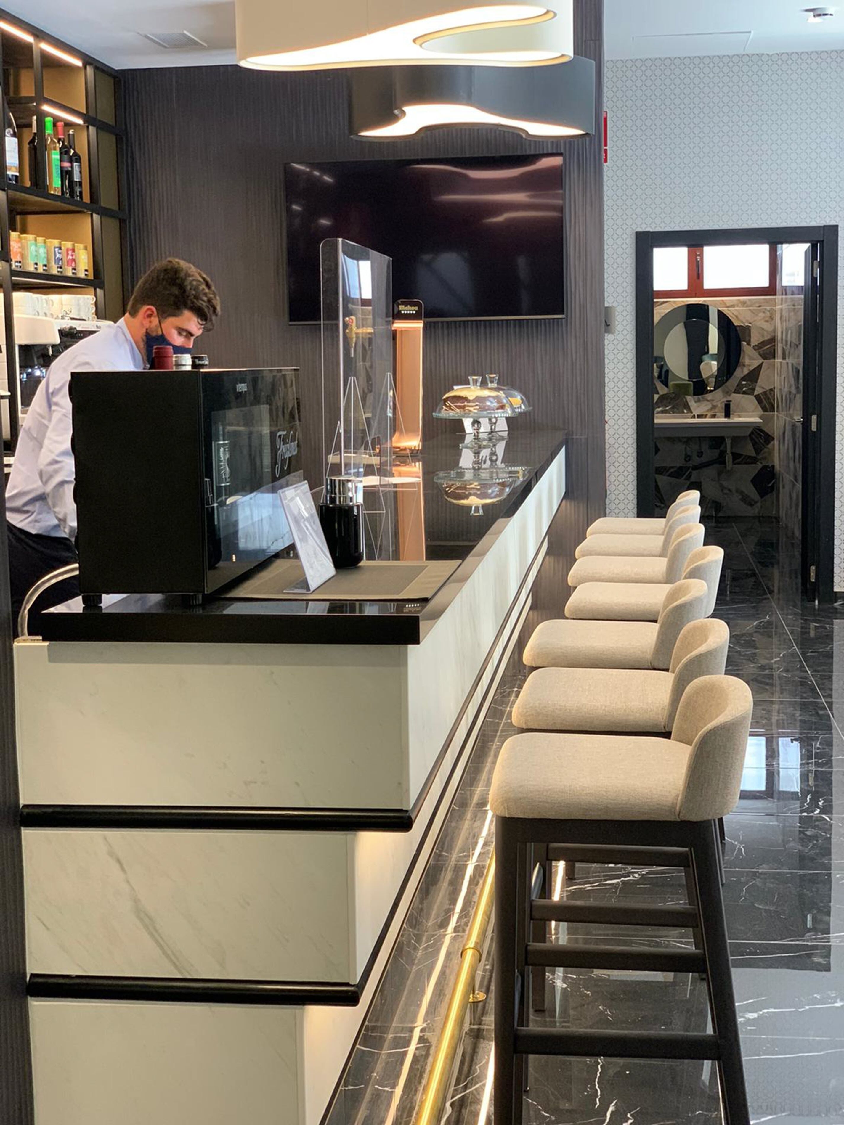 A modern bar area with a counter, bar stools, and a television screen.