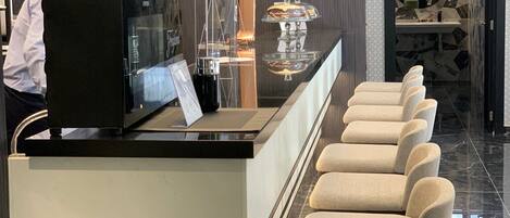 A modern bar area with a counter, bar stools, and a television screen.
