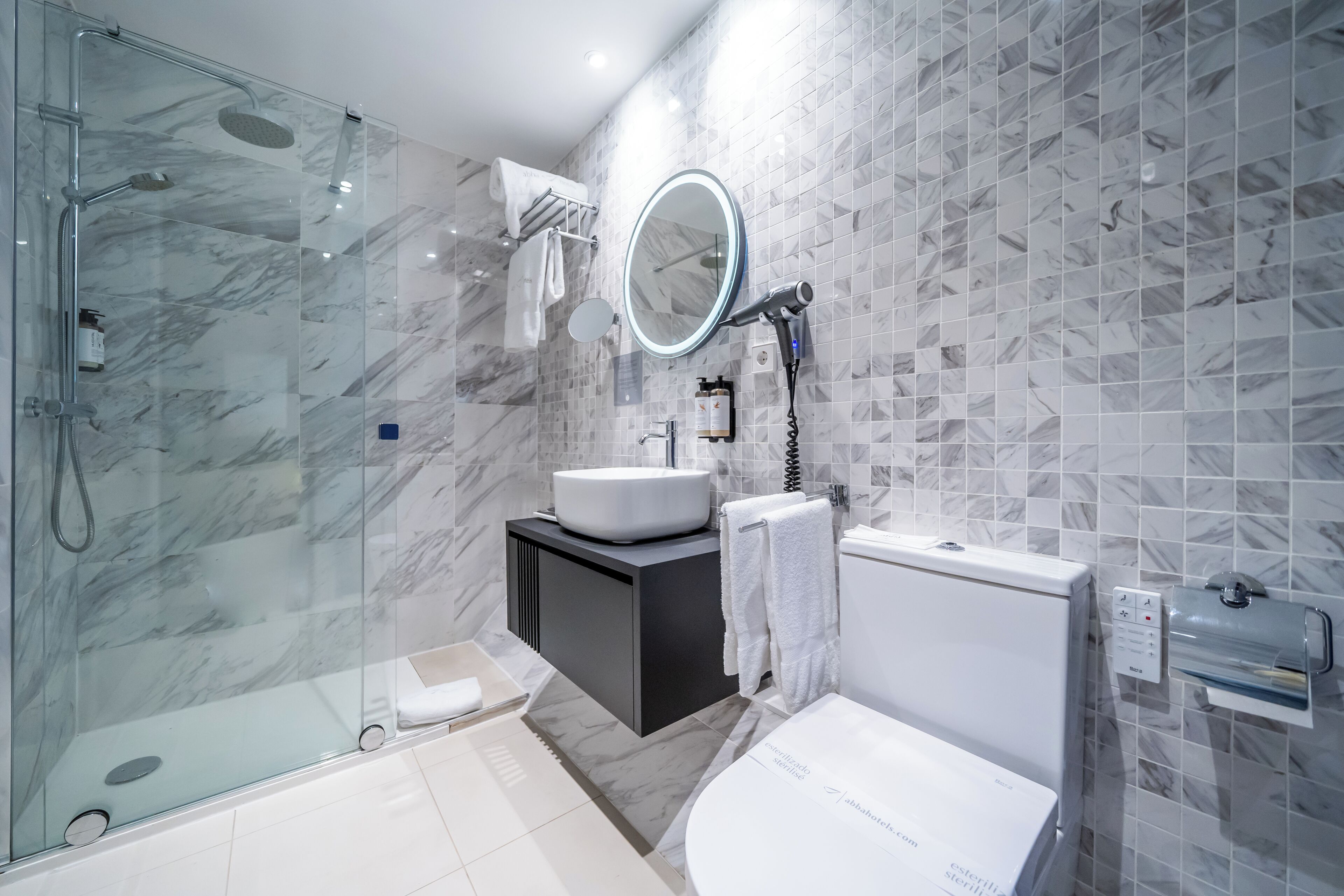 Un bagno moderno con doccia a vetro, lavabo con mobile contenitore, uno specchio grande e una vasca da bagno.