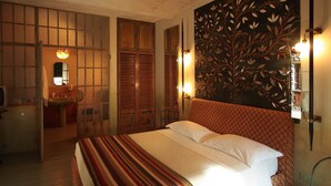 A bedroom with a large bed, a wooden wardrobe, a mirror, and a decorative wall panel. - Locanda Amerigo dal 1934 (Valsamoggia)