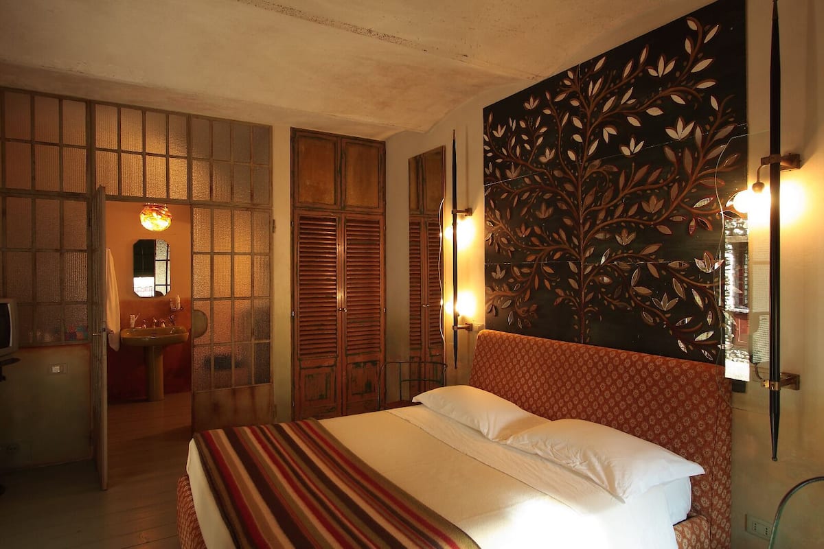 Une chambre à coucher avec un grand lit, une armoire en bois, un miroir et un panneau décoratif mural.