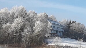 Un edificio grande de dos pisos rodeado de árboles cubiertos de escarcha.