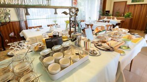 Una mesa con una variedad de alimentos y utensilios para servirlos, dispuesta tipo bufé.