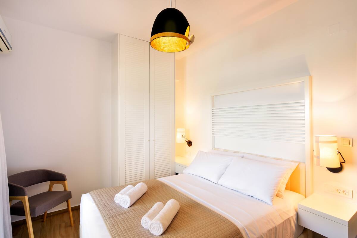 A hotel room with a bed, bedside lamps, a chair, and a wardrobe.