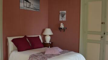 A bedroom with a bed, a chandelier, a nightstand, and a door.