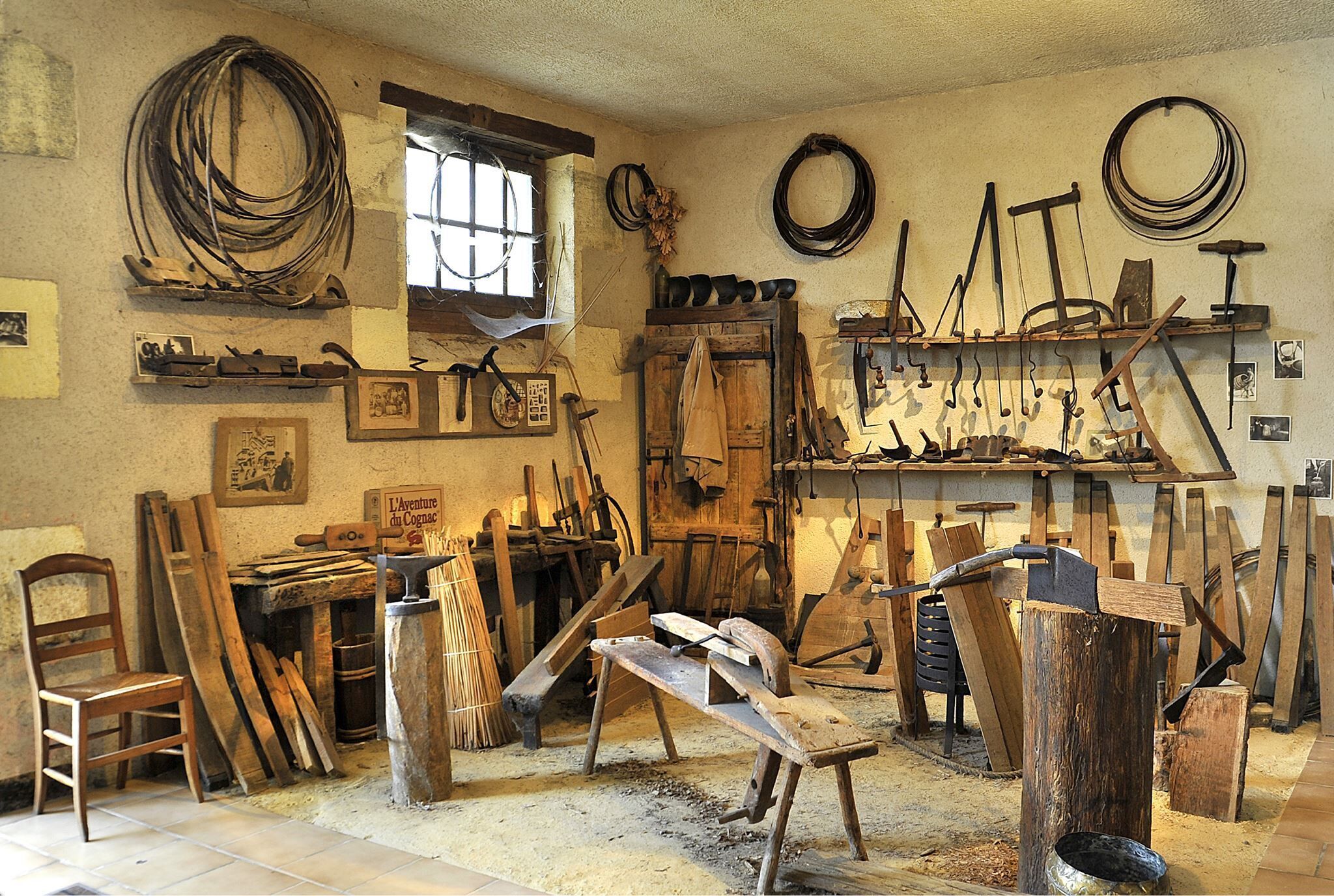 Un atelier équipé de divers outils et matériels, notamment des marteaux, des planches et un établi.