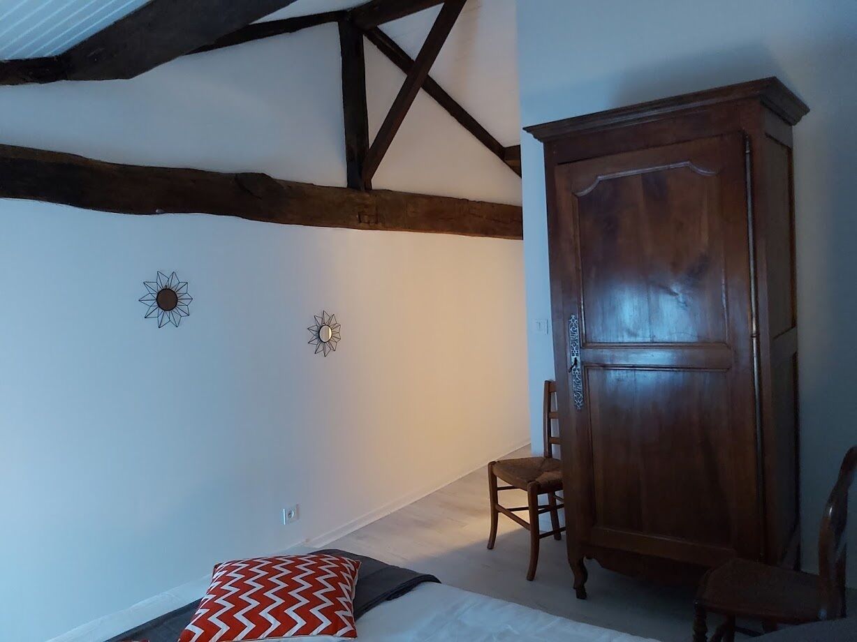 A room with a bed, a wooden wardrobe, and a chair.