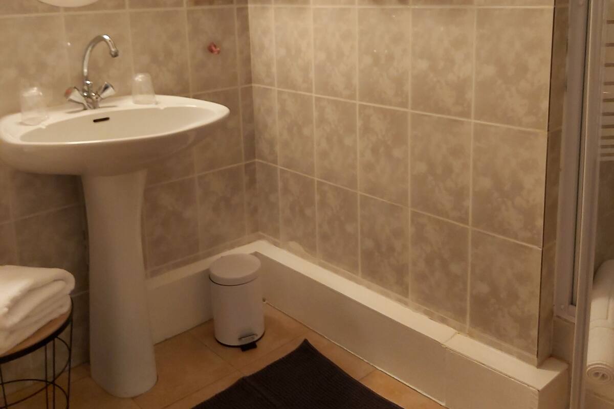 Un baño con lavamanos, espejo y toallero.