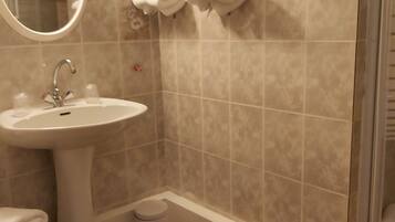 Un baño con lavamanos, espejo y toallero.