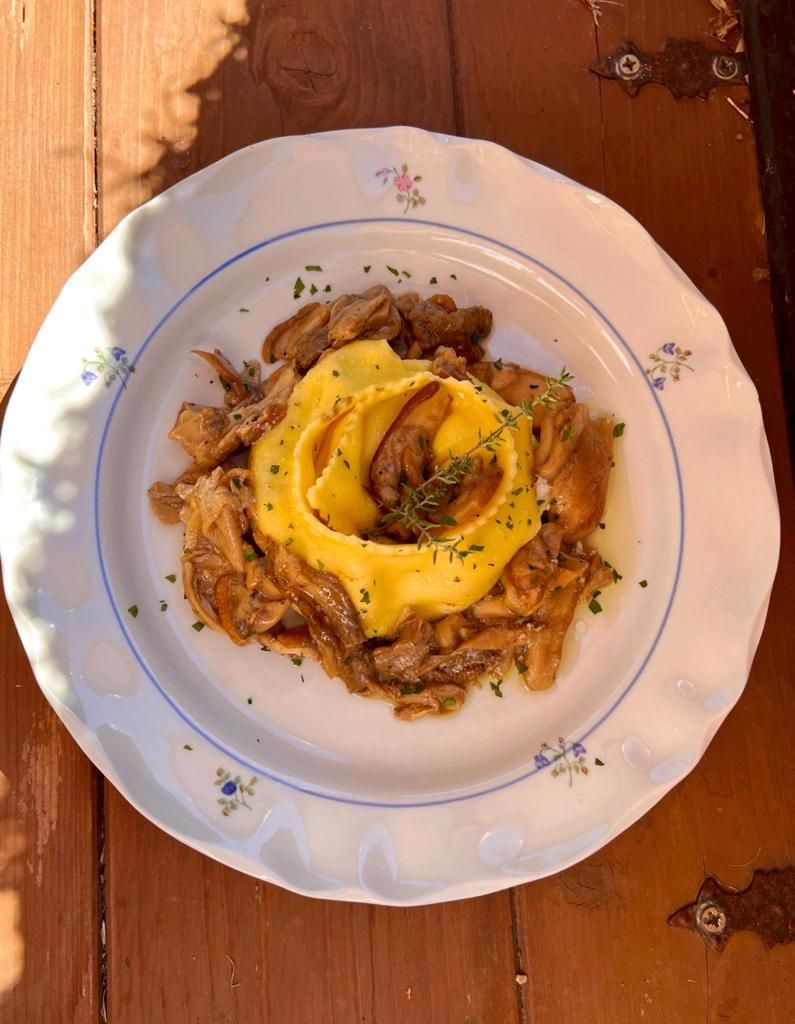Ein Teller mit Fleisch und Kartoffelpüree, garniert mit Kräutern, auf einem Holztisch.