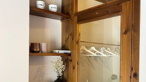 A wooden door with a frosted glass panel, wooden shelves with various items, and a hanging rack with clothes. - Agriturismo Rio Verde (Sasso Marconi)
